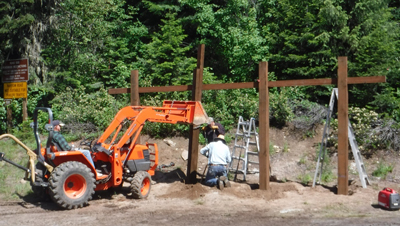 Timber sign-frame being erected by 3 men